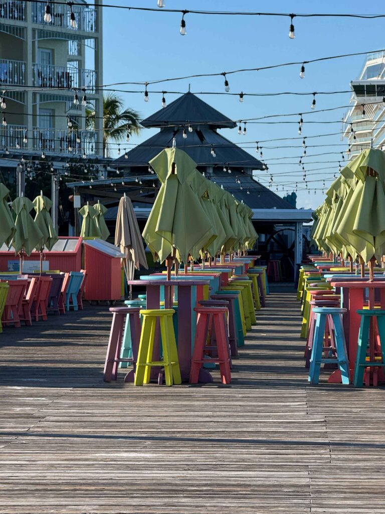 sunset pier with green umbrellas and tropical colored tables